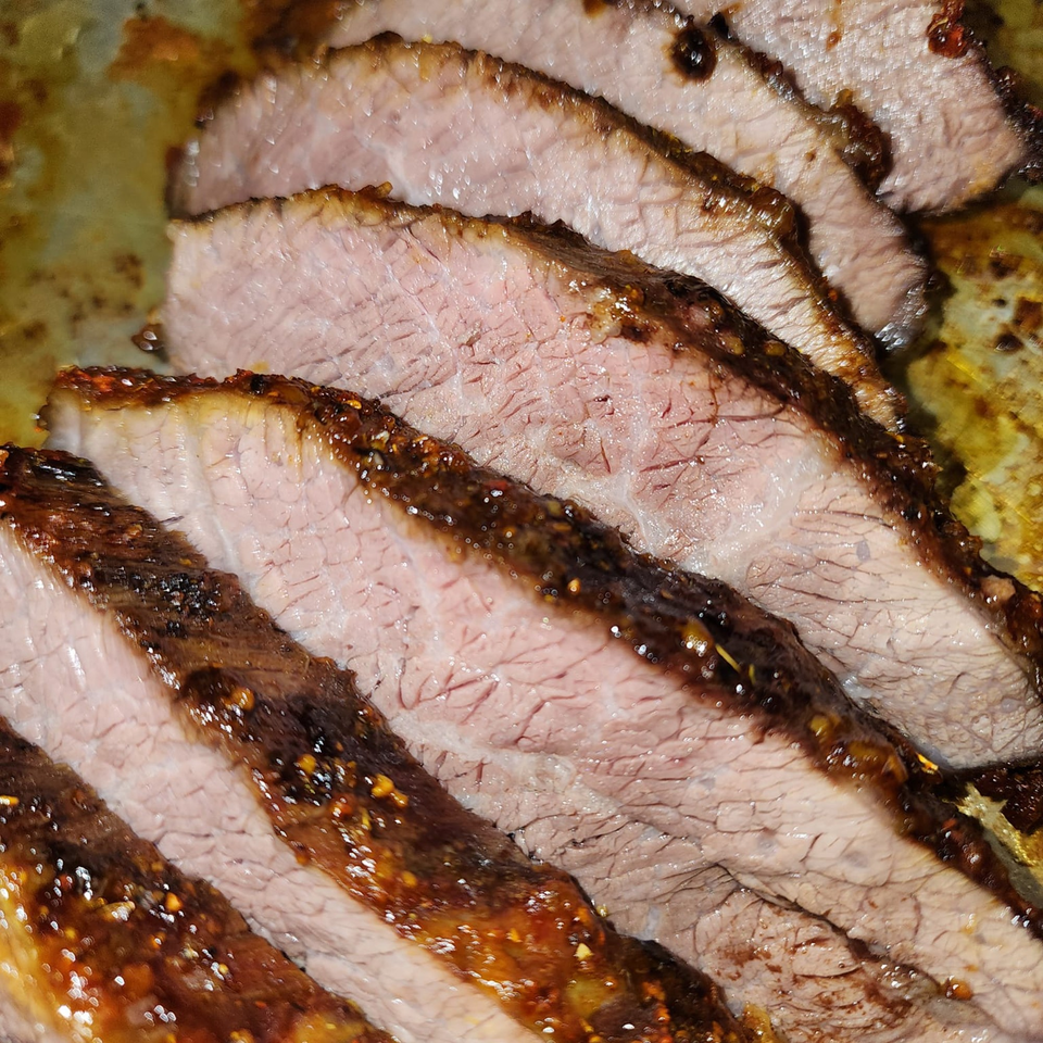 Close-up of several slices of Levy's Soul Cafe's juicy, seasoned brisket with a dark, crispy crust.